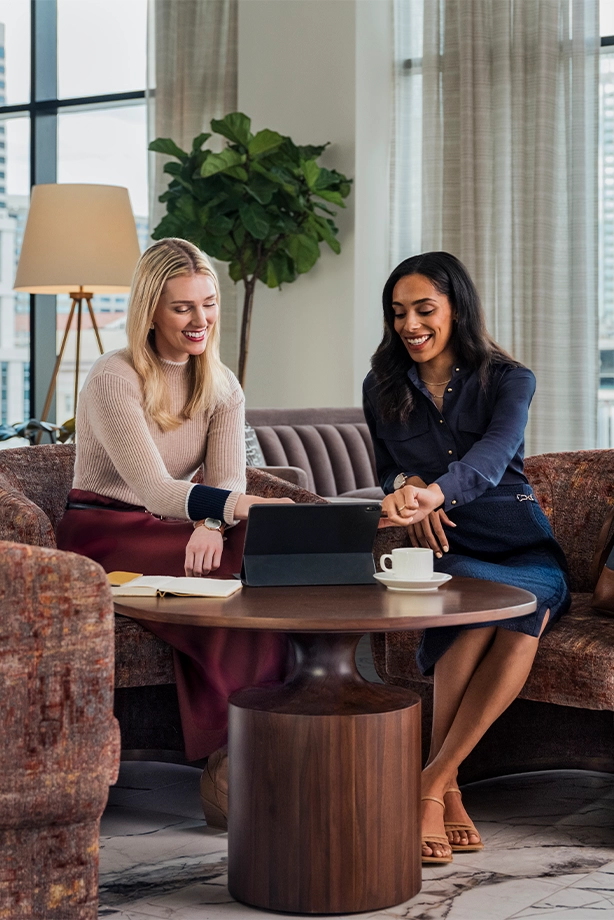 Business women at a tablet drinking coffee in a hotel lounge.